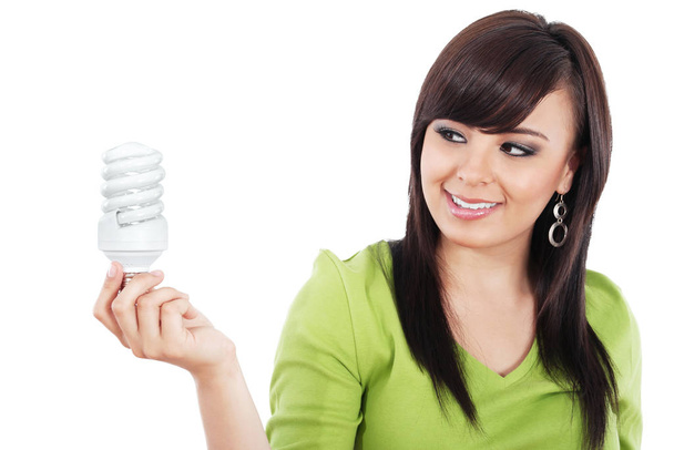 Stock image of young woman looking at compact fluorescent lightbulb isolated on white background - Foto, Imagen