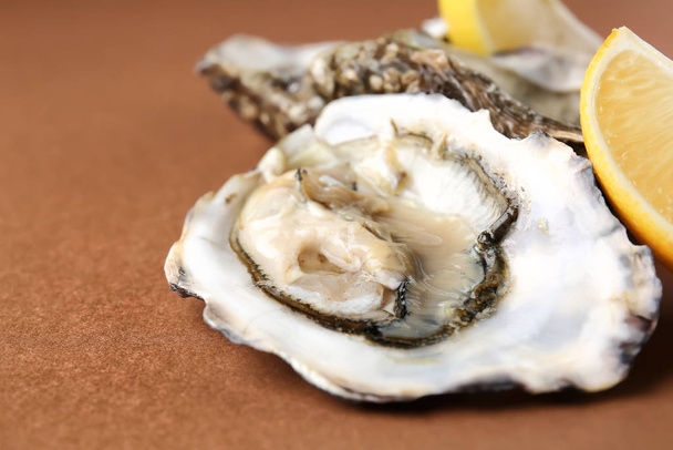 Tasty oysters with lemon on color background, closeup - Foto, Imagem