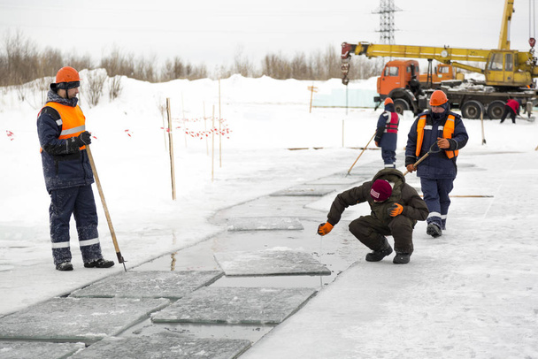 Працівник вимірює товщину льоду в ставку
 - Фото, зображення