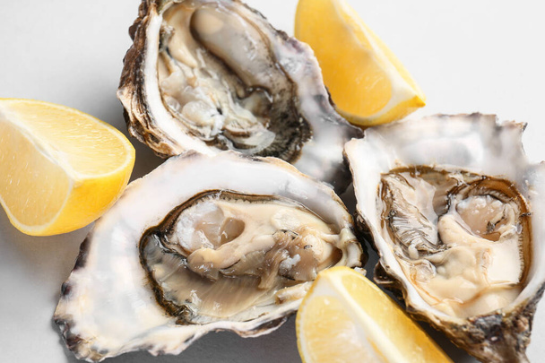Tasty oysters with lemon on white background, closeup - Foto, Imagen