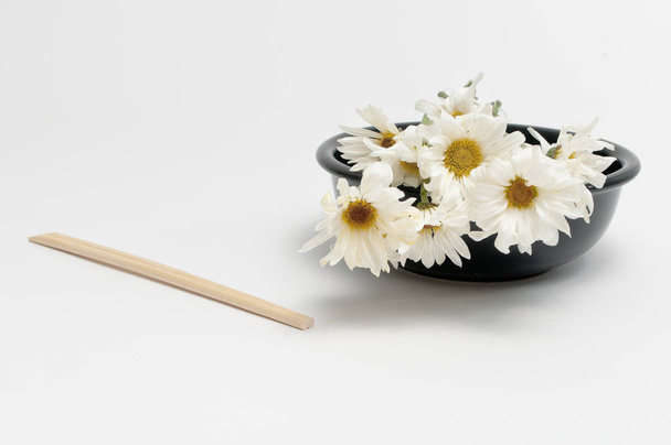 A Bunch of White Daisies in a Black Bowl with Chopsticks - Foto, afbeelding