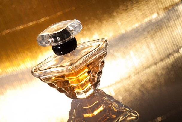 Perfume bottle with reflection on abstract golden background - Foto, imagen