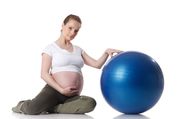 The active pregnant woman does sports exercises on a white background. Care of health and pregnancy. - 写真・画像