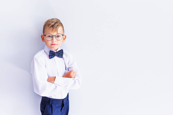 A small cheerful, cute, fashionable blond boy with glasses looks at the camera trying on glasses.The concept of health. Vision correction. Ophthalmology. - Photo, image