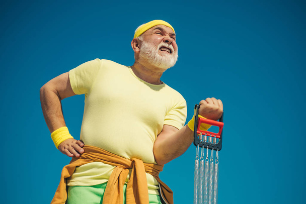 Elderly man after her workout. Senior man exercising on blue sky. Senior sport man is doing sport outdoors. - Fotó, kép