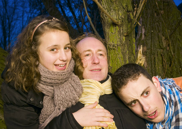 portrait of a father with his two teenage teenagers in front of a tree at dusk - Fotografie, Obrázek