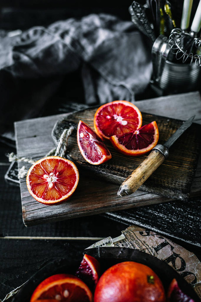 Naranjas rojas frescas con rodajas en una tabla de madera antigua vintage
 - Foto, Imagen