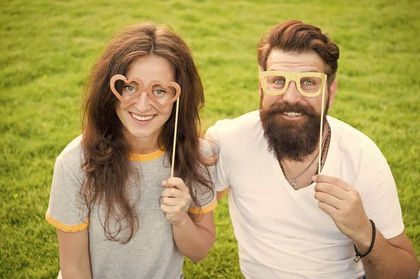 Love story. Happy together. Couple in love cheerful youth booth props. Couple relaxing green lawn. Man bearded hipster and pretty woman in love. Summer vacation. Emotional couple radiating happiness - Foto, immagini