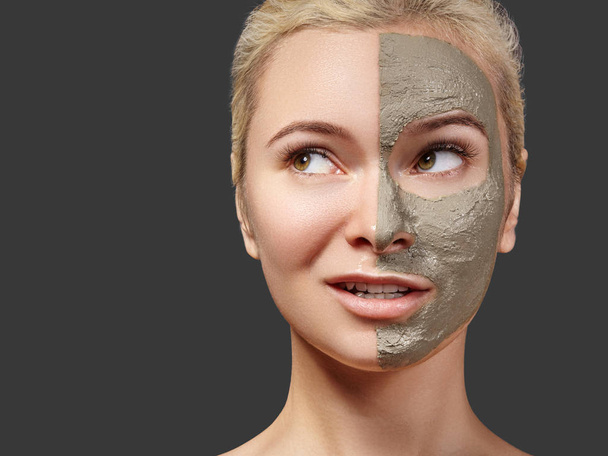Beautiful Woman Applying Facial Mask. Beauty Treatments. Spa Girl Apply Clay Facial Mask on Grey Background. Funny Face - Фото, изображение