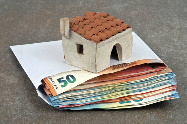 Piccola casa su una busta di banconote in euro da vicino su sfondo bianco
 - Foto, immagini
