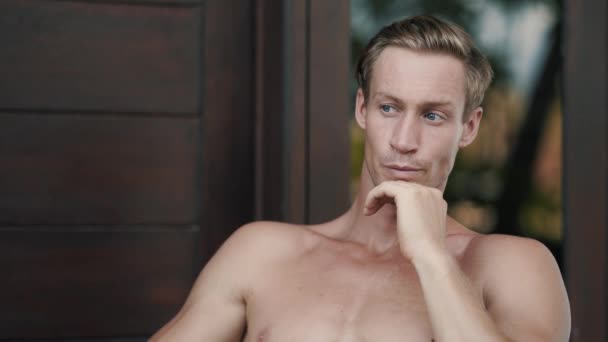 Portrait of handsome shirtless blond man looking at camera, smiling and flirting - Footage, Video