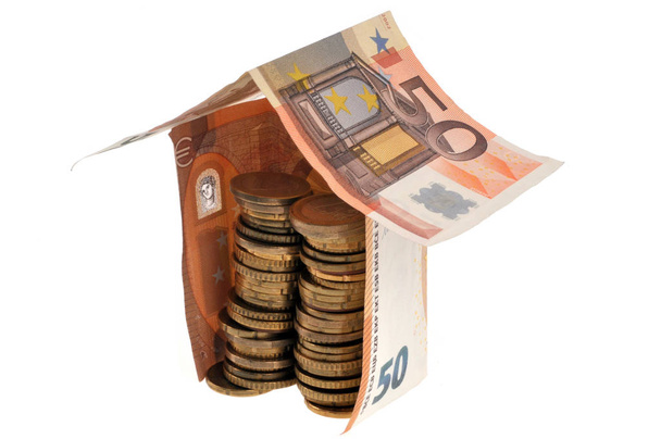 Haus in Euro-Banknoten mit Münzen in Nahaufnahme auf weißem Hintergrund - Foto, Bild