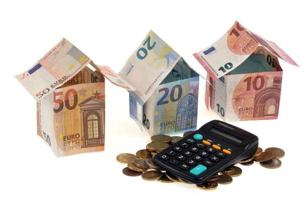 Haus in Euro-Banknoten mit Münzen, Taschenrechner in Nahaufnahme auf weißem Hintergrund - Foto, Bild