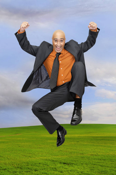Happy businessman jumping outdoors in a green field - Foto, Bild