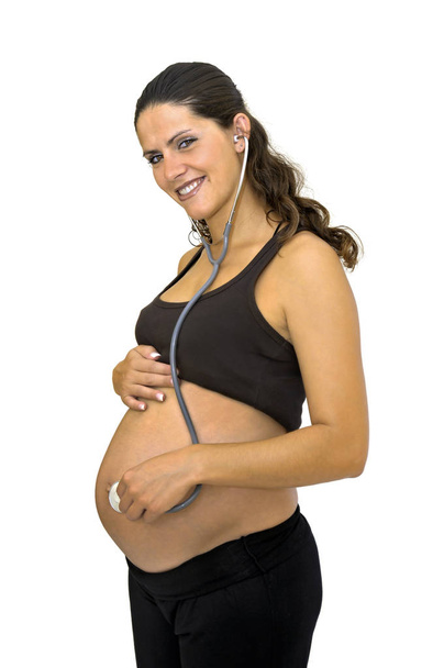 Pregnant woman with stethoscope listening to her belly isolated in white - Foto, immagini