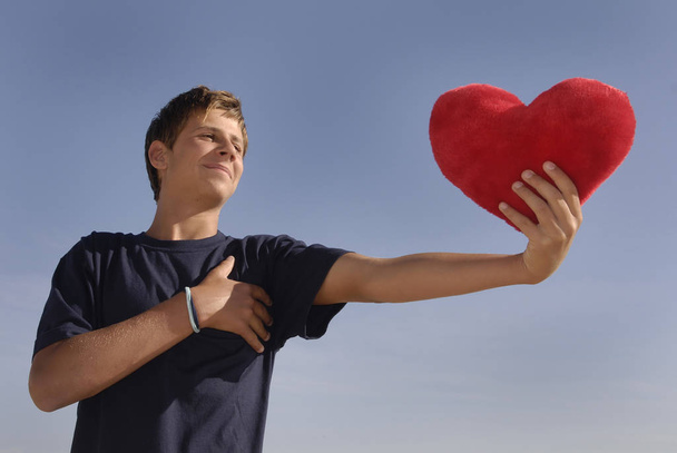 Boy in love holding a big red heart - 写真・画像