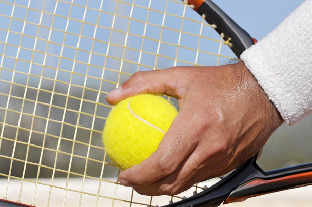 Player's hand with tennis ball preparing to serve - Foto, imagen