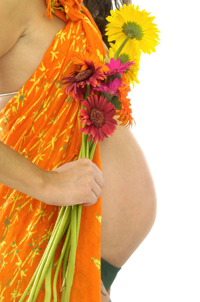 Pregnant woman belly with orange rag and flowers isolated in white - Фото, изображение
