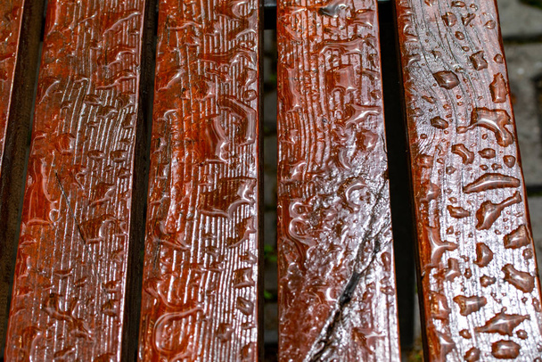 Gotas de lluvia en un banco de madera de cerca
. - Foto, Imagen