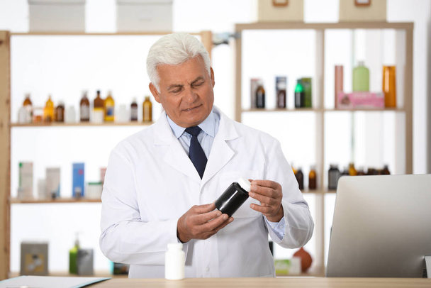 Professional pharmacist with bottle of medicine in drugstore - Фото, зображення