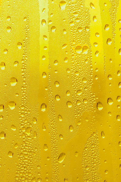 Druppels water op het glas, gele achtergrond bier, misted achtergrond. - Foto, afbeelding