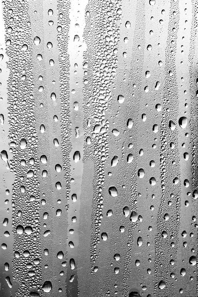 Gotas de lluvia en el vidrio, fondo blanco y negro, textura de vidrio de moda
. - Foto, imagen