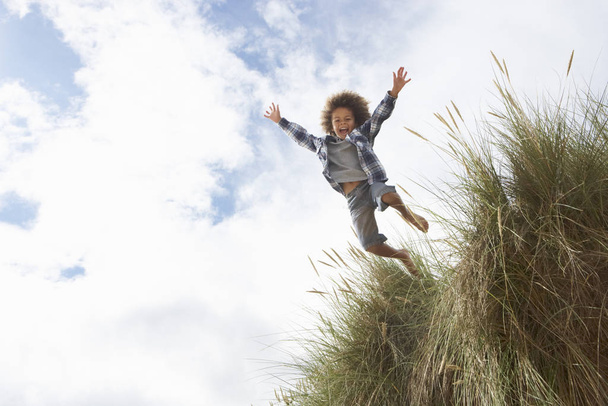 Boy jumping over dune - Fotó, kép