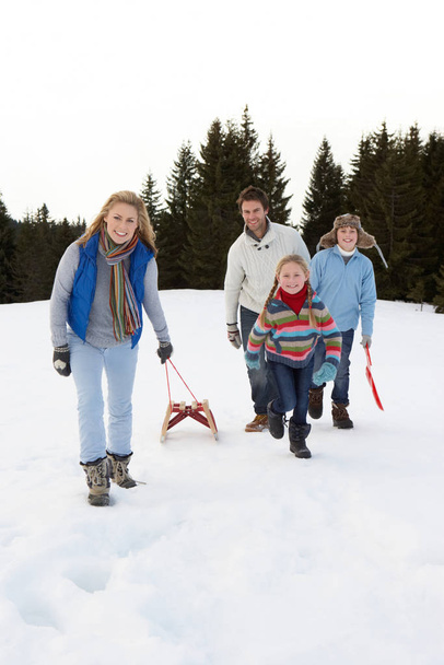 Young Family Walking Through Snow With Sled - Foto, imagen