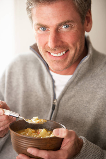 Man eating bowl of soup - Foto, afbeelding