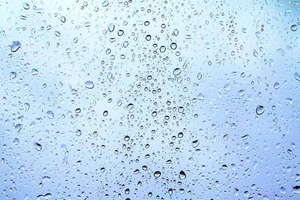 Gotas de lluvia en el vidrio, fondo azul oscuro del cielo fuera de la ventana
. - Foto, Imagen