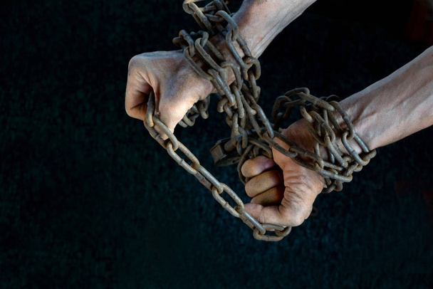 Manos de un esclavo tratando desesperadamente de romper la cadena de hierro
 - Foto, Imagen