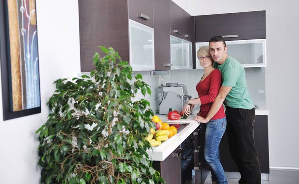 happy young couple have fun in  modern kitchen indoor  while preparing fresh fruits and vegetables food salad - Foto, afbeelding