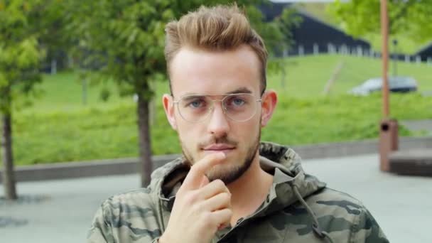 Portrait of young man with glasses looking at camera - Кадри, відео