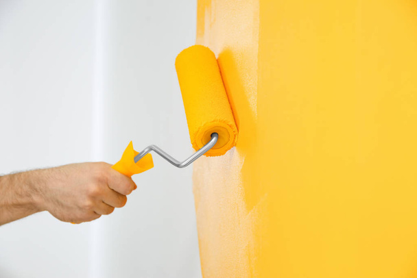 Man painting white wall with yellow dye, closeup. Interior renovation - Фото, зображення
