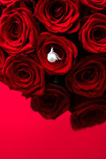 Bellissimo anello di perle in oro bianco e bouquet di rose rosse, lusso
 - Foto, immagini