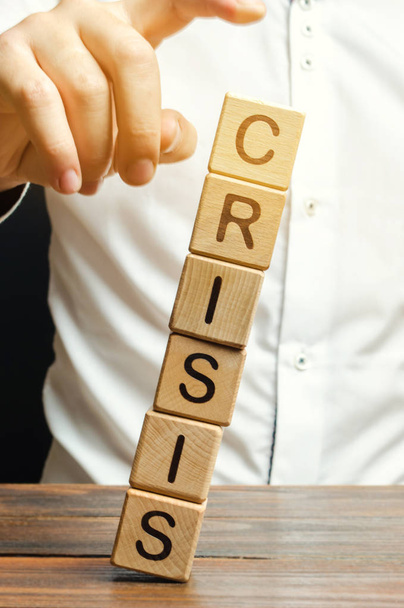 Businessman removes wooden blocks with the word Crisis. The exit from the crisis and financial stability. Focus on resolving the midlife crisis. The rise of the economy and business development. - Photo, image