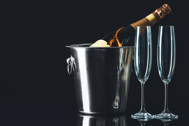 Bucket with bottle of champagne and glasses on dark background - Fotoğraf, Görsel