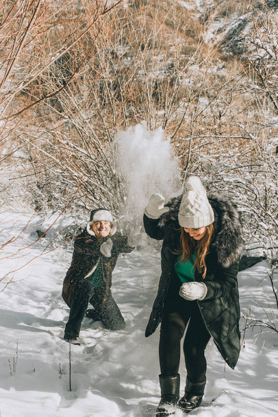  guy and girl play snowballs in winter among the trees. - Foto, Imagen