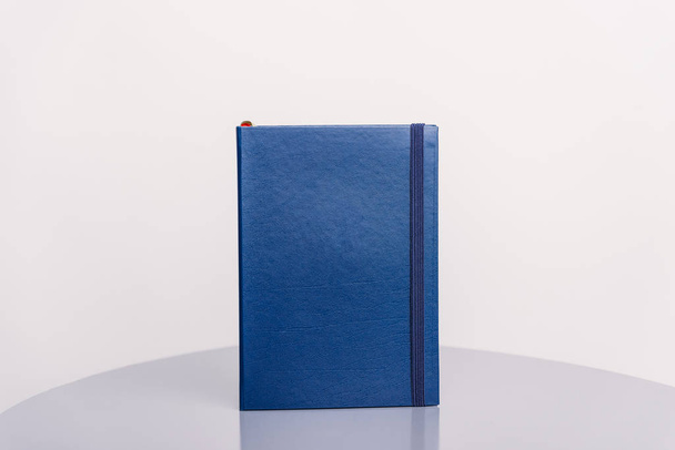 Livro azul marinho, agenda ou planejador em pé sobre uma superfície cinza e fundo branco. Modelo de livro
. - Foto, Imagem