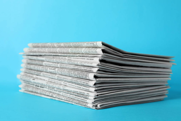 Stack of newspapers on light blue background. Journalist's work - Photo, Image