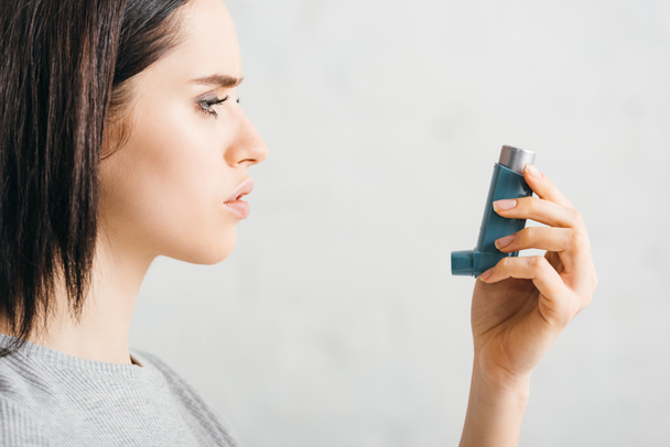 Side view of young woman holding inhaler on white background - Photo, Image