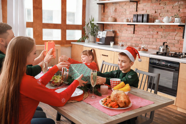 Родители поздравляют своих детей на Рождество во время ужина
 - Фото, изображение