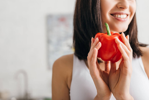 Cropped view of smiling woman holding ripe bell pepper at home - Foto, Imagem