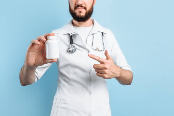 Dokter met een potje medicijnen op een blauwe achtergrond - Foto, afbeelding