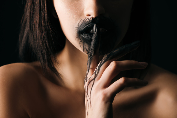 Vista ritagliata di donna nuda con labbra dipinte nere e mano che mostra il gesto del silenzio isolato sul nero
   - Foto, immagini