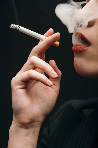 Oříznutý pohled ženy kouřící cigarety izolované na černém  - Fotografie, Obrázek