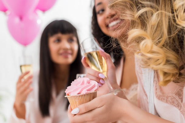 foyer sélectif de filles multiculturelles heureuses s'amuser avec du champagne et cupcake pendant la fête de célibataire
  - Photo, image