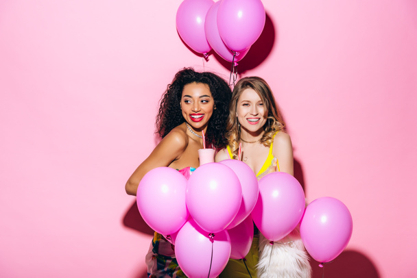 novias sonrientes multiculturales sosteniendo batidos en rosa con globos
 - Foto, Imagen