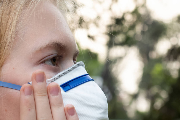 Menina loira usando P2 N95 proteção máscara respiratória para reduzir a quantidade de partículas respiratórias PM2.5
 - Foto, Imagem