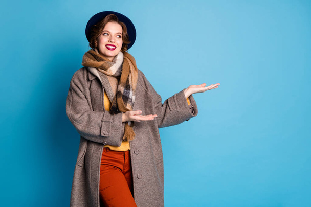 Photo of pretty lady work abroad young professional guide show indicate arms old historical building wear stylish casual long grey coat scarf pants hat isolated blue color background - Φωτογραφία, εικόνα